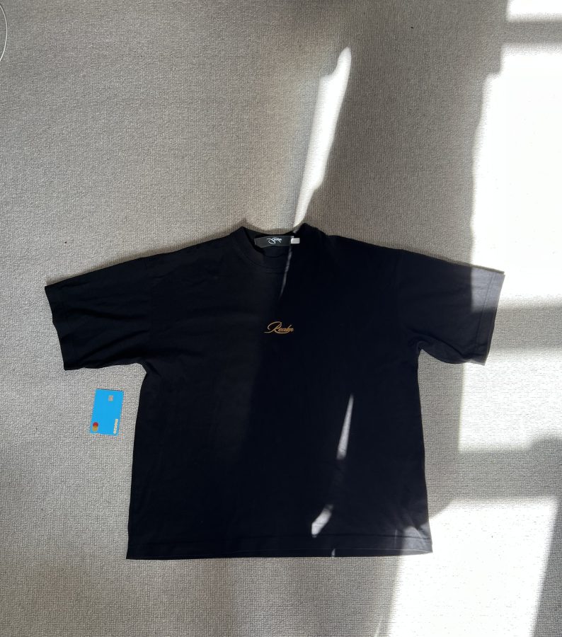 A black t-shirt laid flat with a bank card beside it